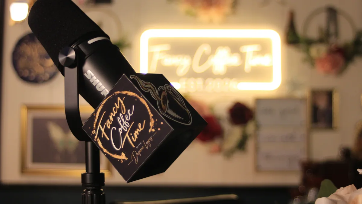 A studio microphone and Fancy Coffee Time sign in a warmly lit set